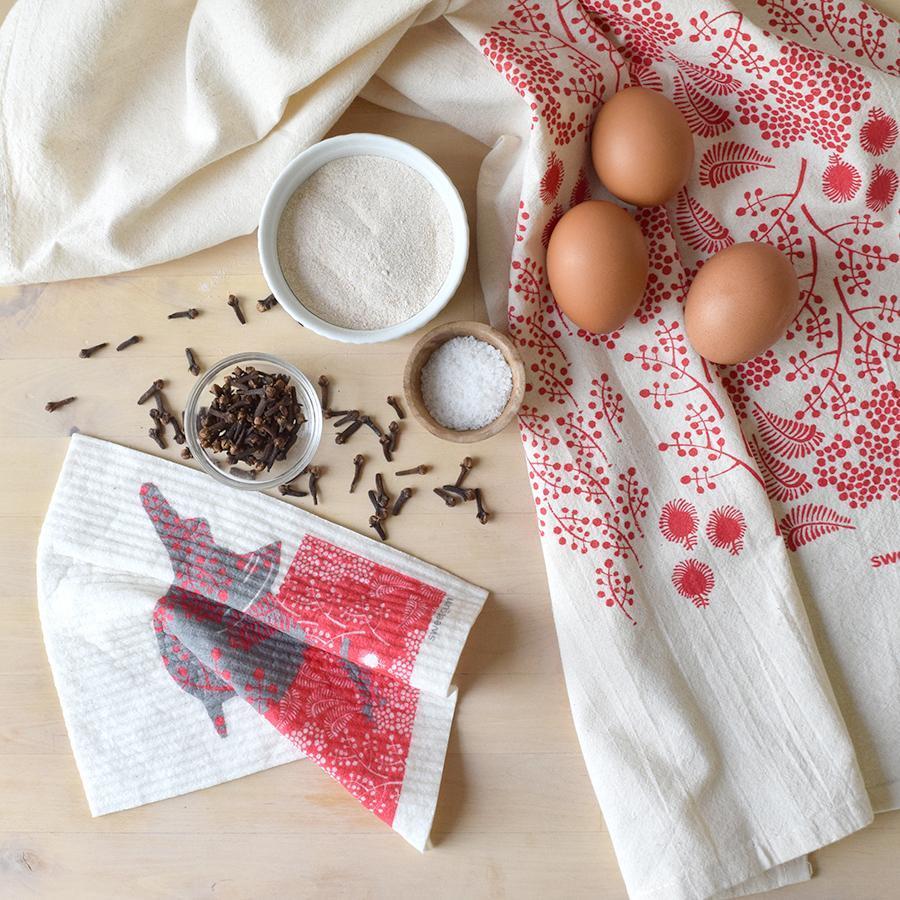 Kitchen Linens featuring decorative towels, eggs, sugar, salt, and spices on a wooden surface.