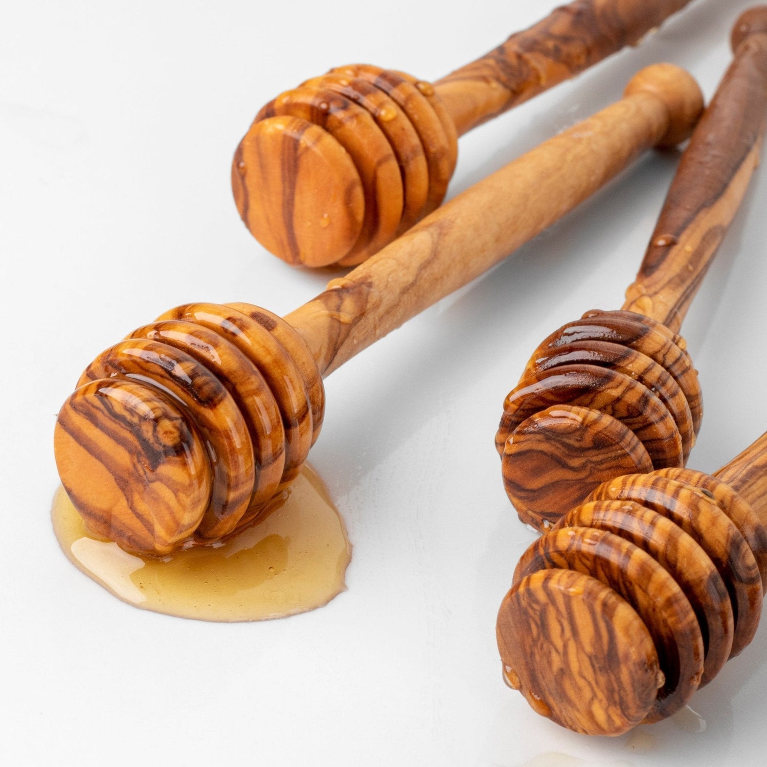 Beekeeping Equipment including wooden honey dippers dripping with honey on a white background.