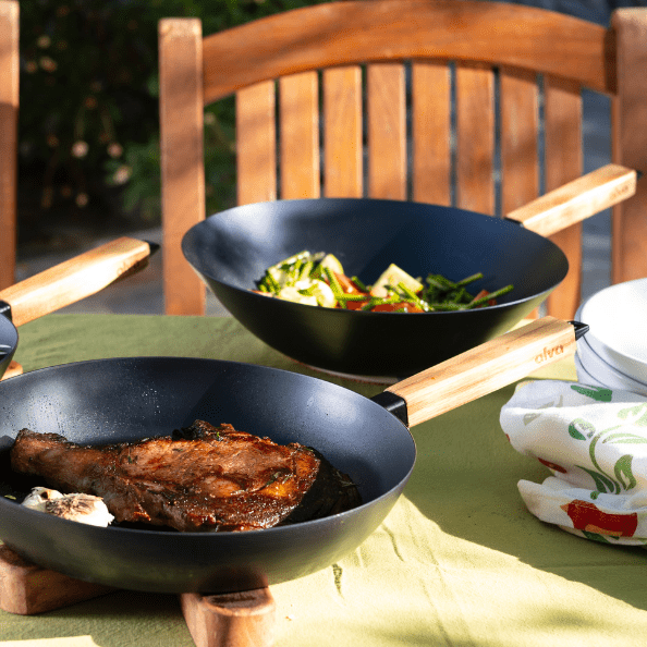 Two woks featuring grilled meat and sautéed vegetables on a table, highlighting the versatility of Woks.