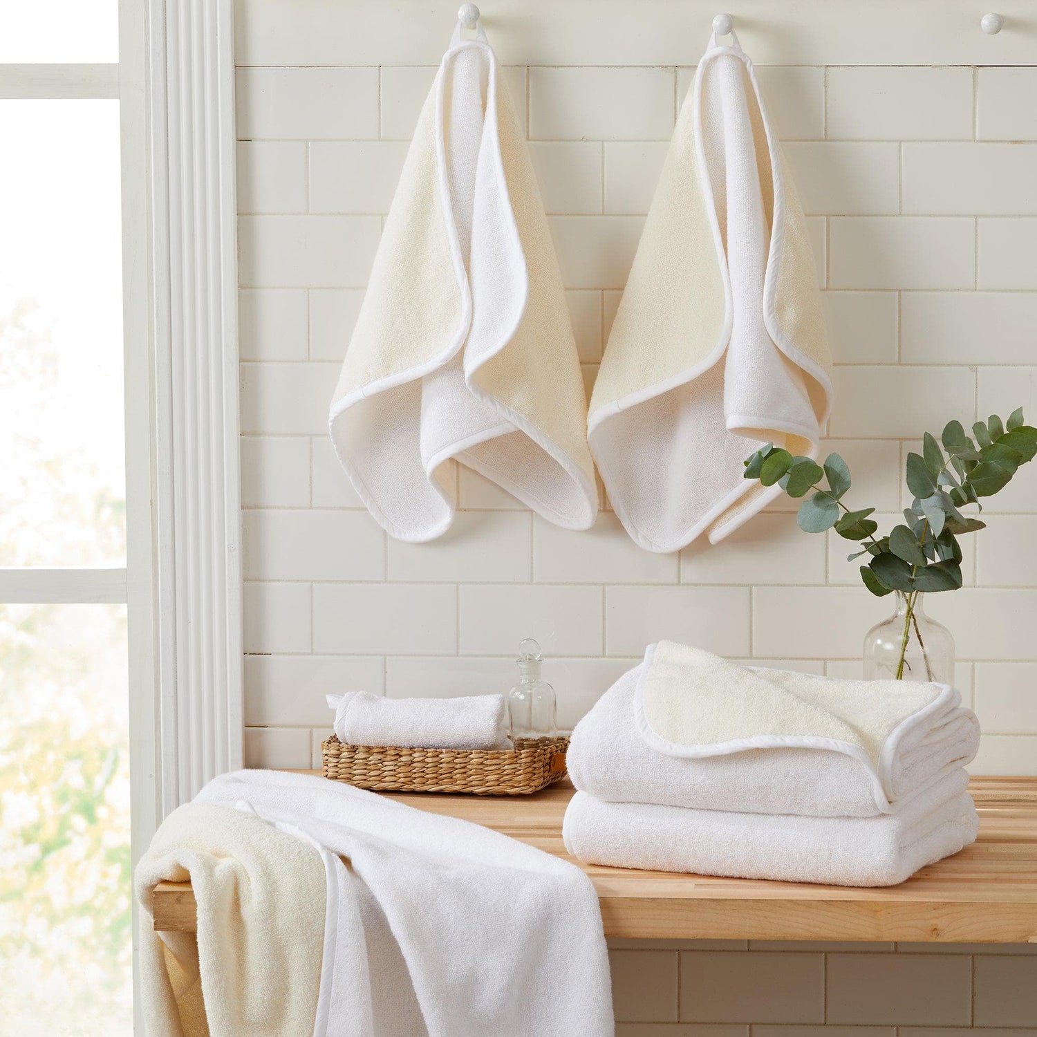 A cozy display of hand towels hanging on hooks and stacked on a wooden table, showcasing soft textures and calming colors.