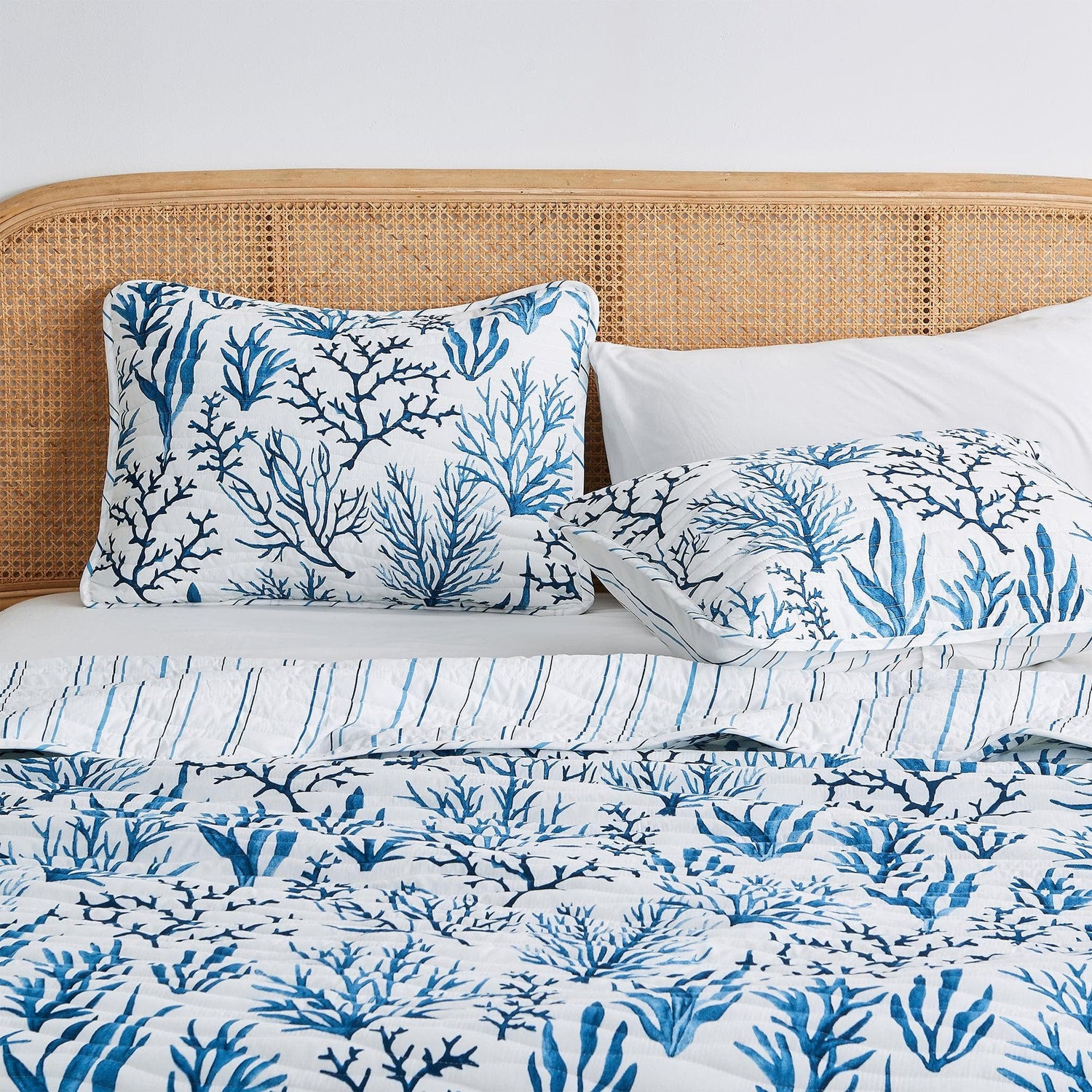 Woven Headboards with blue coral patterned bedding and pillows on a cozy bed.