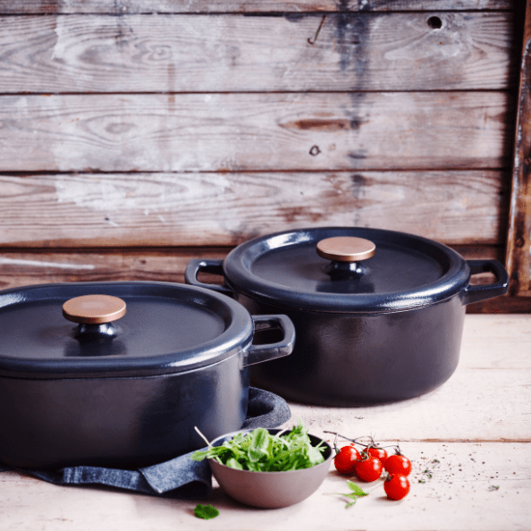 Cast Iron Cookware collection featuring two elegant pots on a rustic wooden table.
