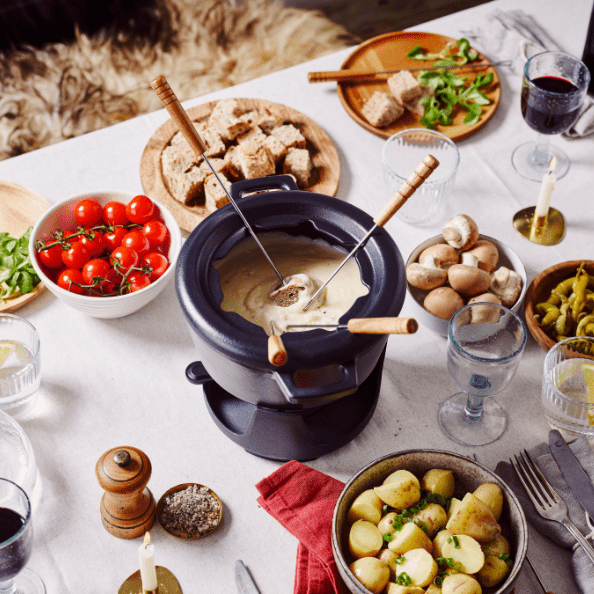 A beautifully arranged table featuring a fondue pot surrounded by various dipping items, showcasing Fondue Pots.
