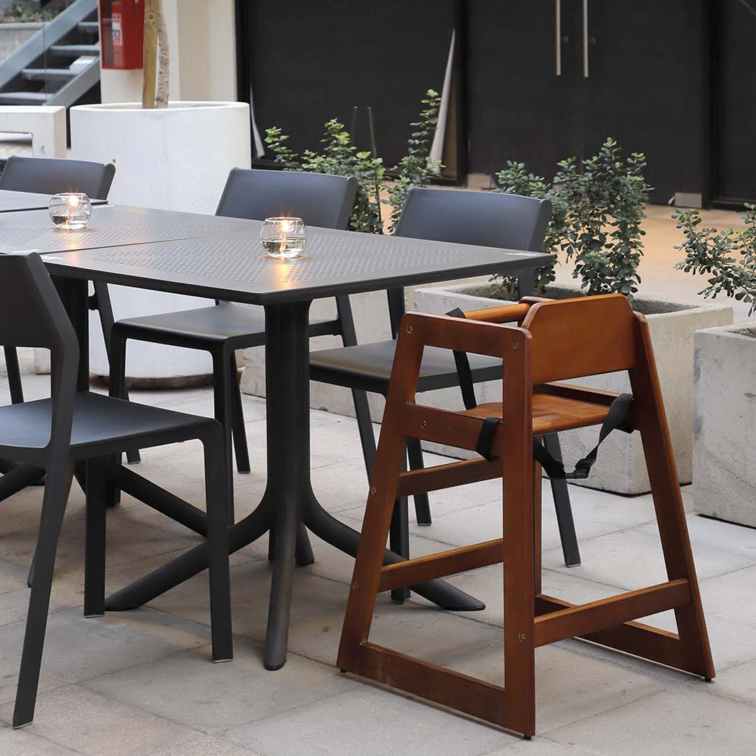 Wooden highchair beside a modern dining table in an outdoor setting, perfect for family dining with highchairs.