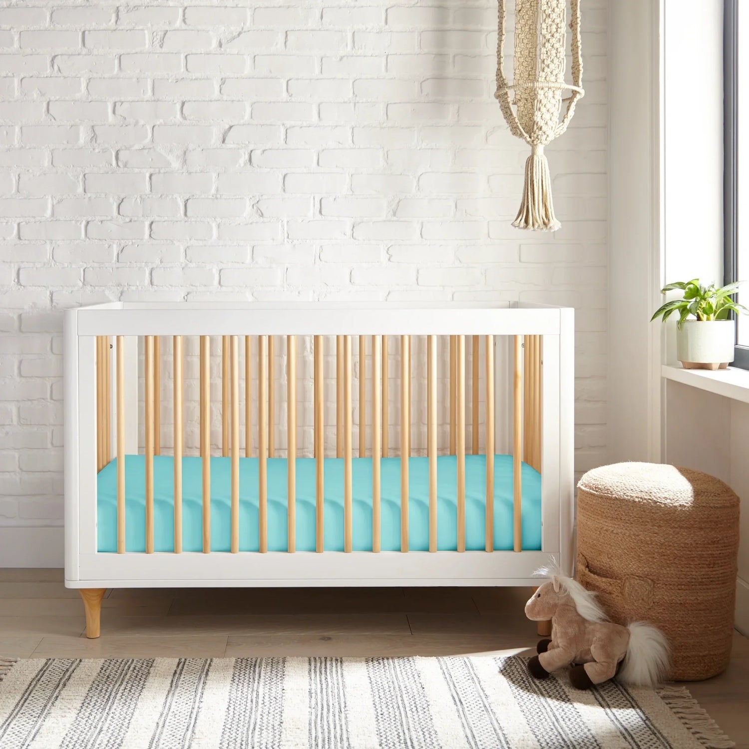 Coastal Nursery featuring a modern crib with a turquoise mattress and minimalist decor in a bright room.