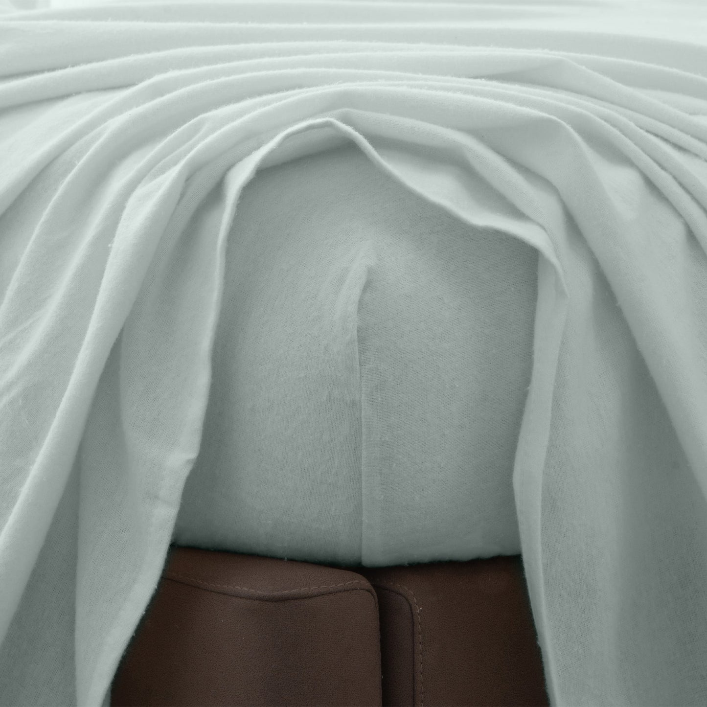 Close-up of gray fitted sheet beneath a top sheet.