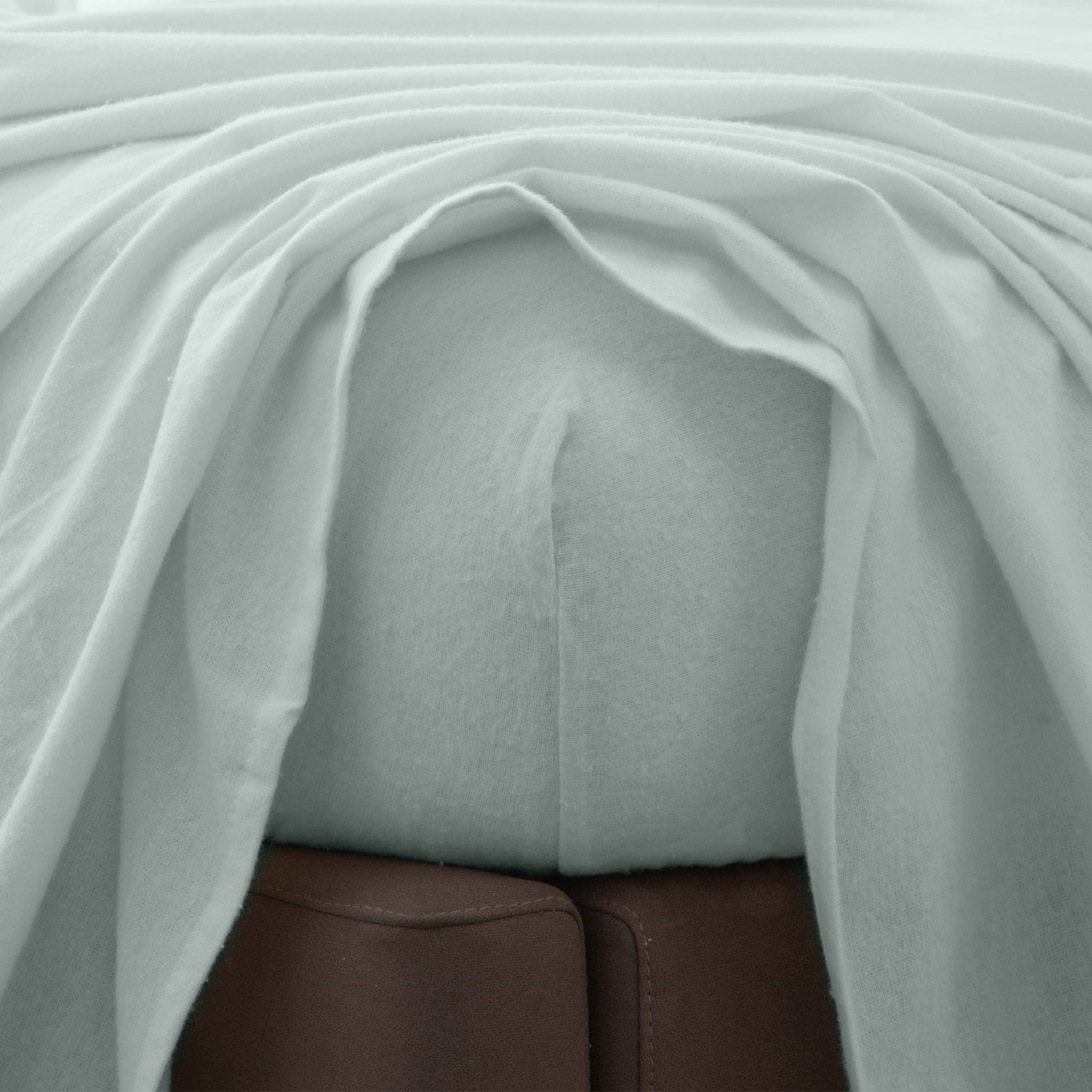 Close-up of gray fitted sheet beneath a top sheet.