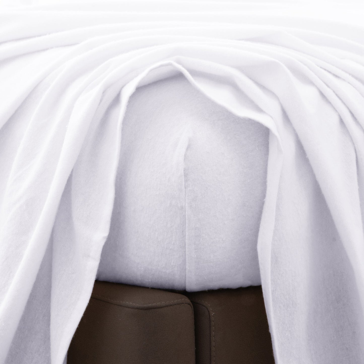 Close-up of a white fitted bed sheet with a top sheet above.
