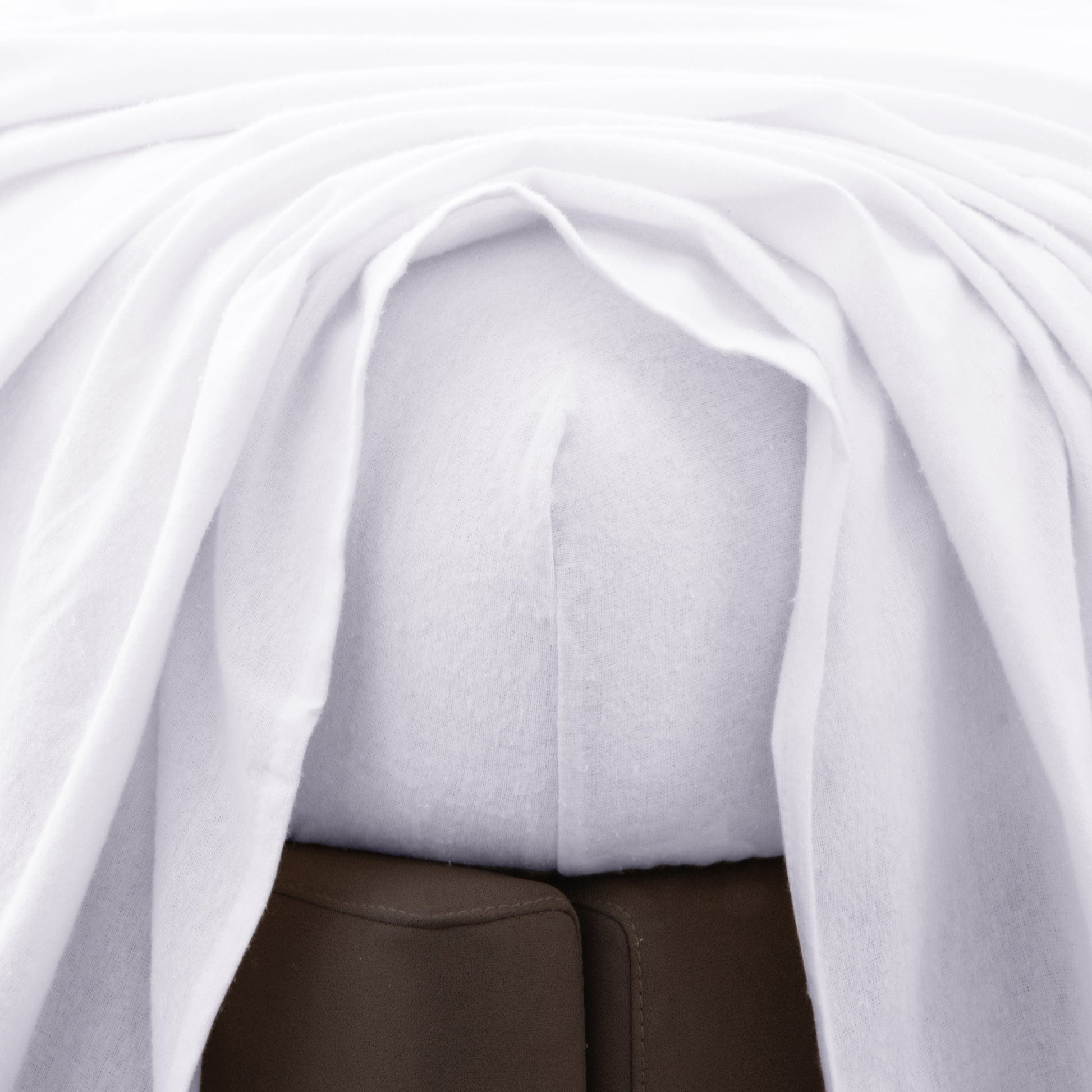 Close-up of a white fitted bed sheet with a top sheet above.