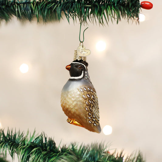 Glass quail ornament hanging on a Christmas tree with lights in the background