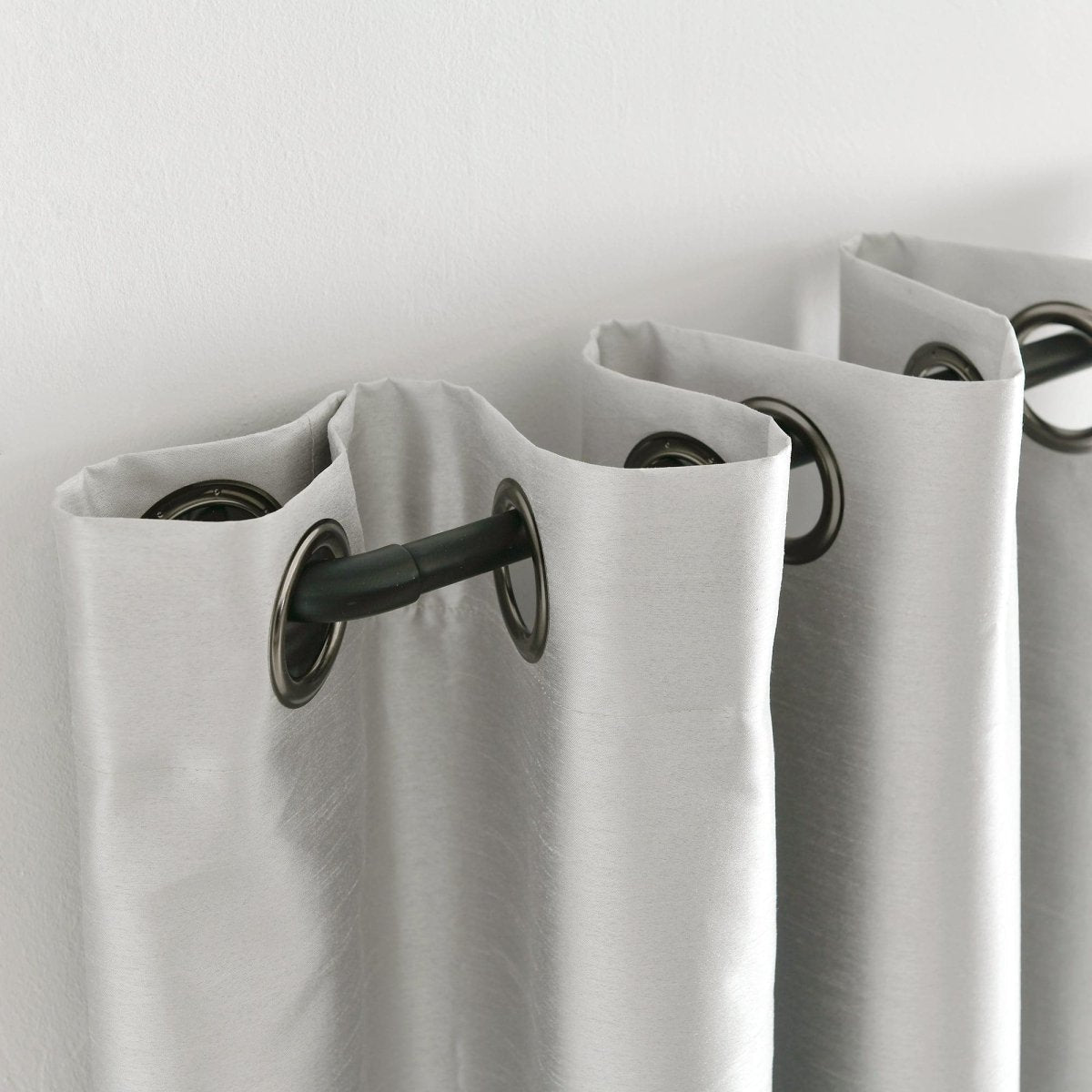 Close-up of Faux Silk 100% Blackout Window Curtain with grommets on a rod, showcasing its luxurious texture.