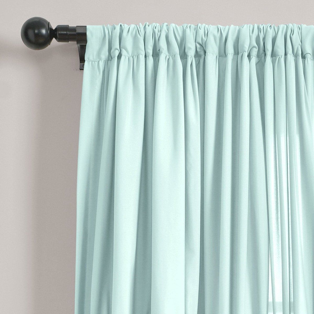 Darla Window Curtain in soft mint green hanging from a black curtain rod, showcasing elegant fabric folds.