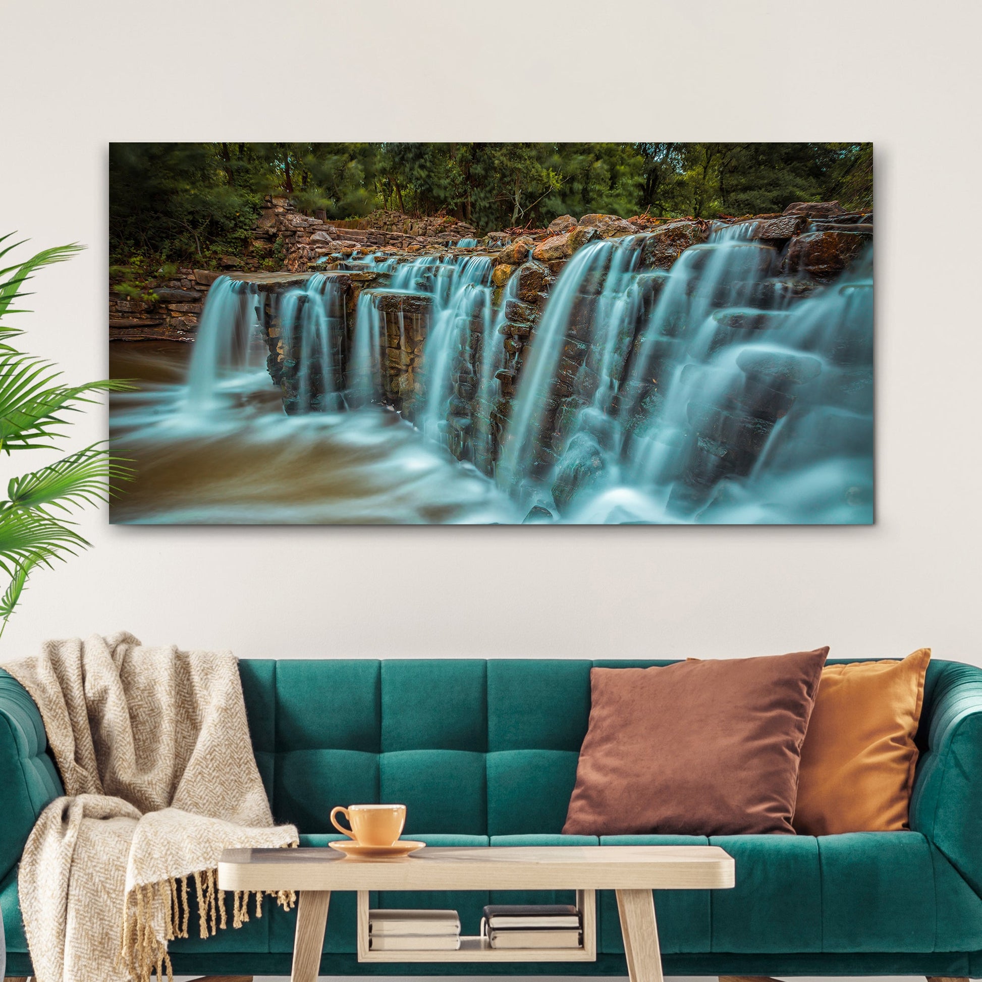 Living room with a teal sofa, coffee table, and large waterfall painting on the wall.