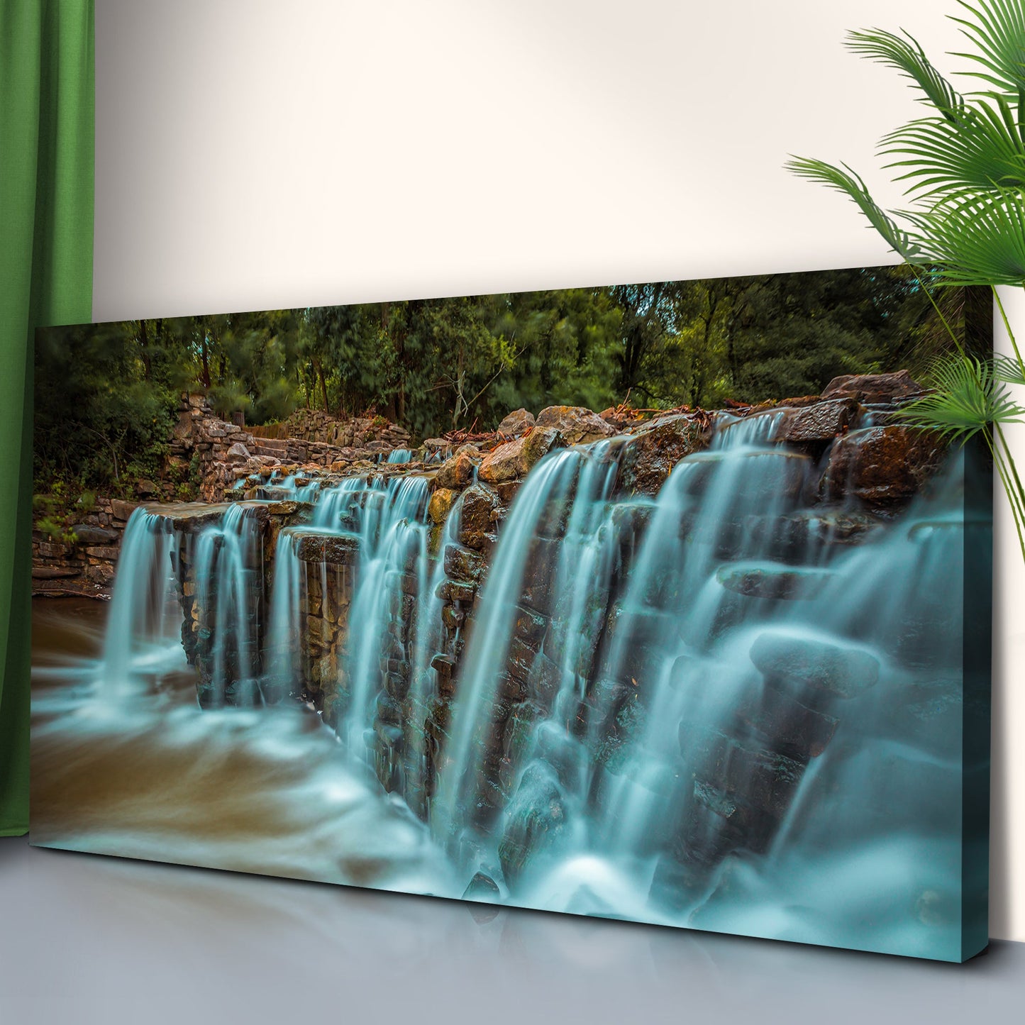 Canvas print of a waterfall in a forest setting on a white wall.