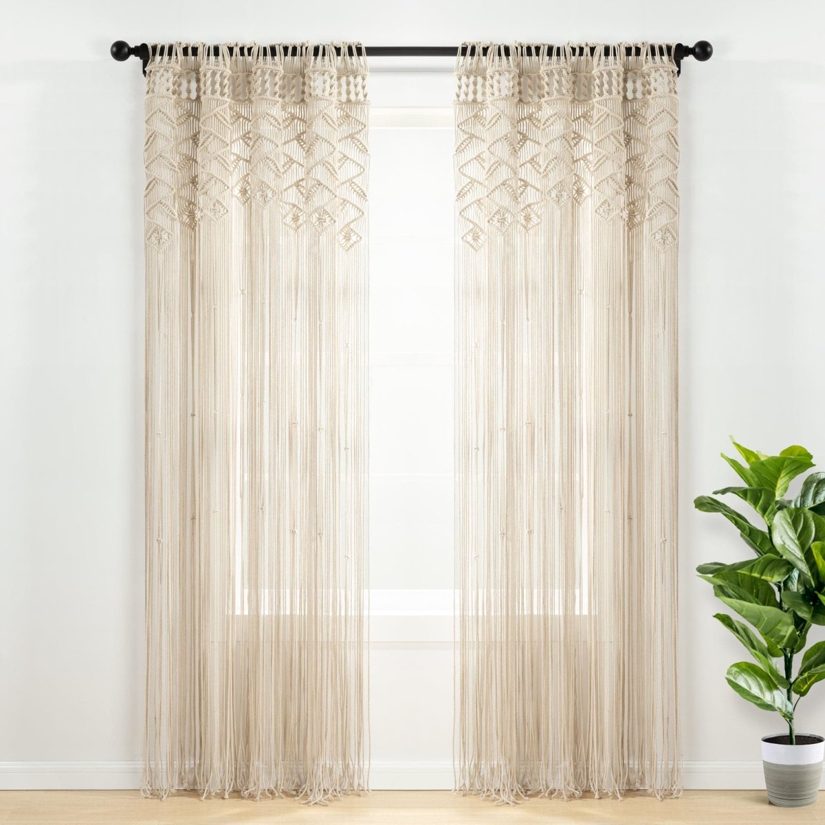 Boho Macrame Leaf Cotton Window Curtain showcasing intricate knots and flowy fringe in a bright room with a green plant.