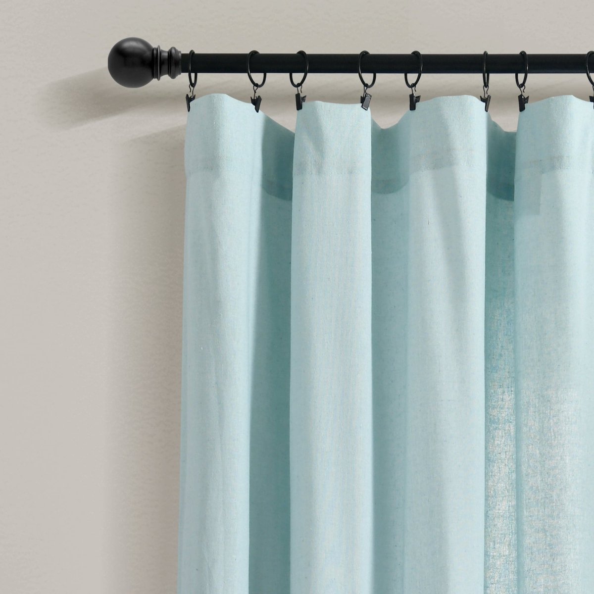 Linen Button Botanical Garden Window Curtain hanging from a black curtain rod, showcasing soft, airy blue fabric.