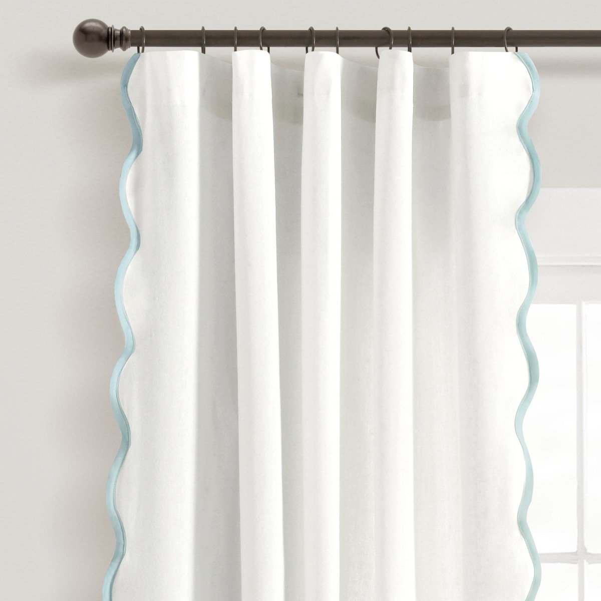 Coastal Chic Scalloped Edge Window Curtain Panel Set hanging from a rod with scalloped edges and sheer white fabric.