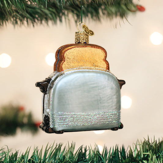 Glass ornament shaped like a toaster with bread slices on a Christmas tree.