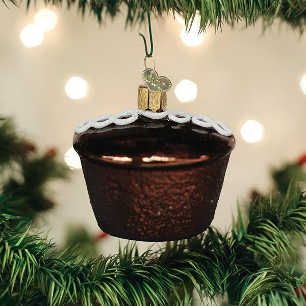 Chocolate cupcake ornament hanging on a Christmas tree with lights in the background