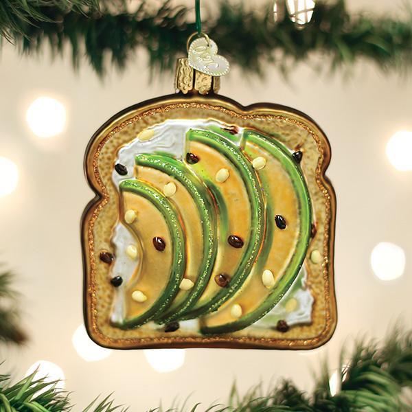 Avocado toast ornament hanging on a Christmas tree with lights in the background
