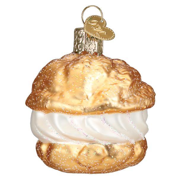 Glass ornament shaped like a pastry with white cream on a white background