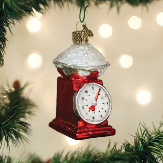 Decorative kitchen scale ornament on a Christmas tree with blurred lights in the background