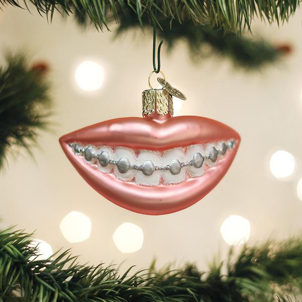 Decorative ornament shaped like lips with braces hanging on a Christmas tree.