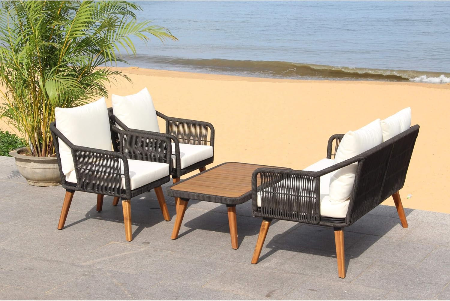 Outdoor Patio 4 Piece Eucalyptus Rope Furniture Set with black rope detailing and eucalyptus wood table by the beach.