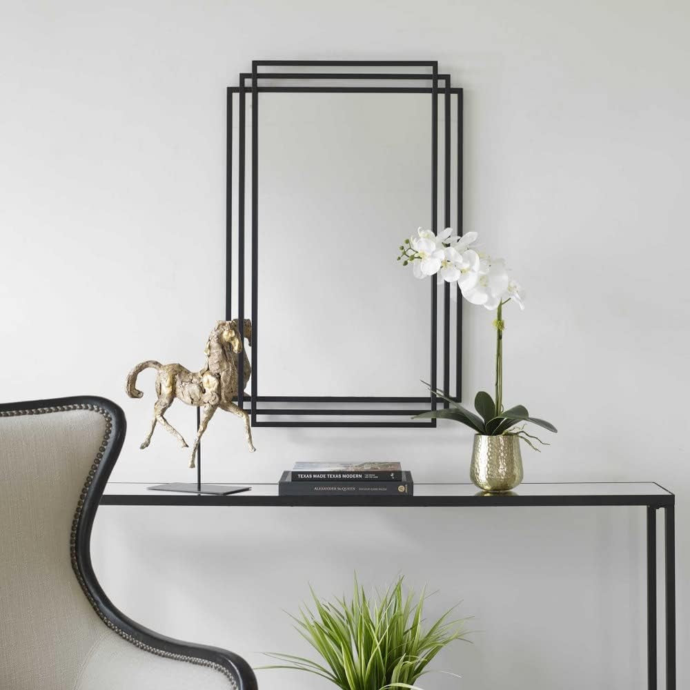 Amherst Matte Black Iron Mirror above a console table with decorative items and plants.