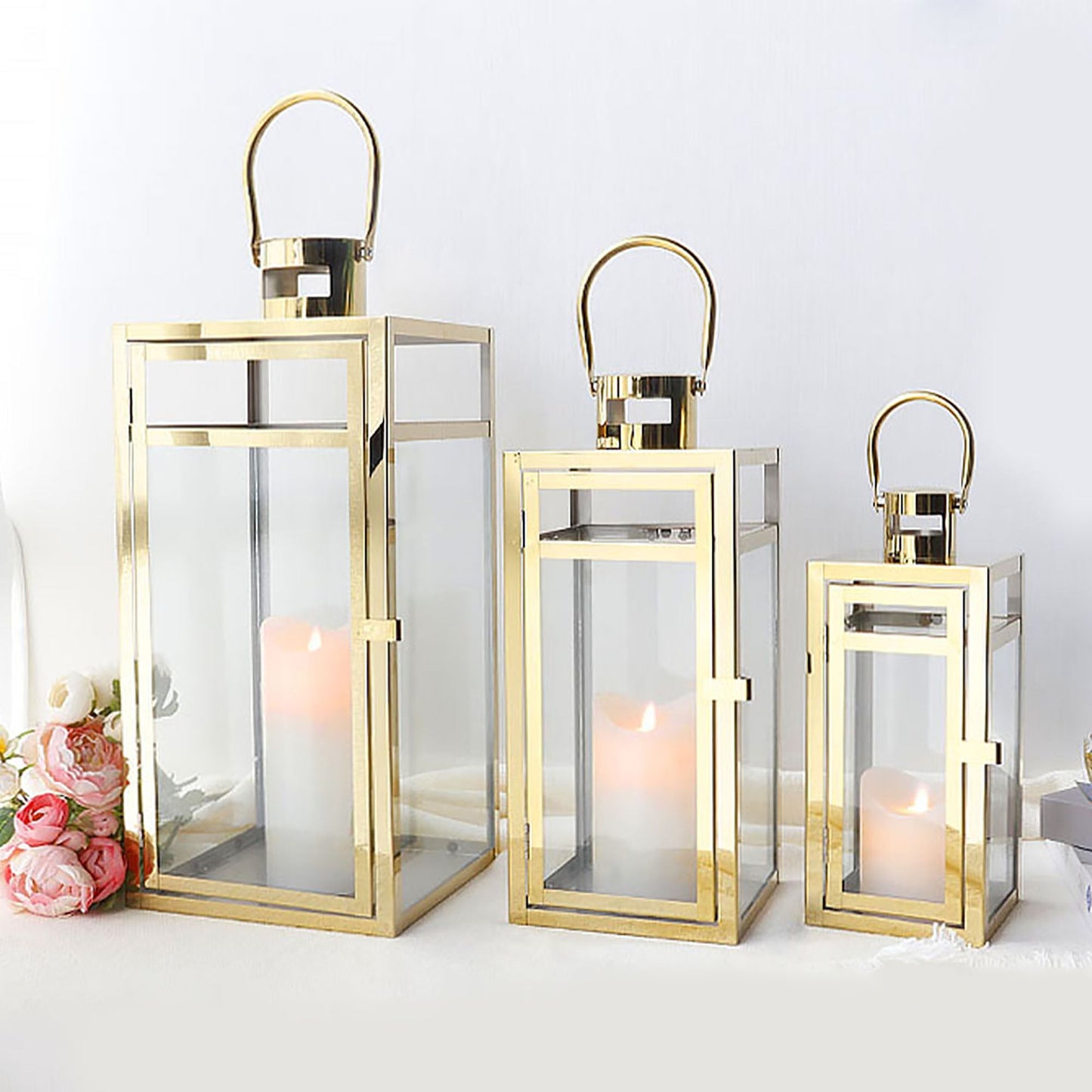 Set of 3 Stainless Steel Lanterns Gold displayed in various sizes with candles inside.