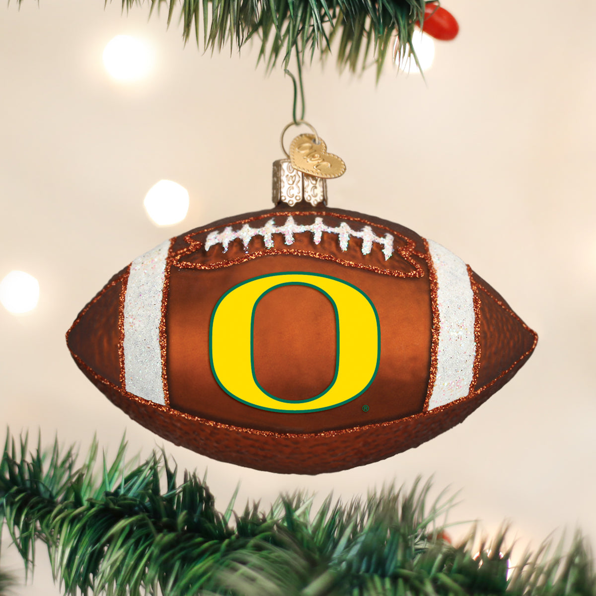 Oregon Football Ornament hanging on a Christmas tree with lights, featuring the Oregon logo on a football design.
