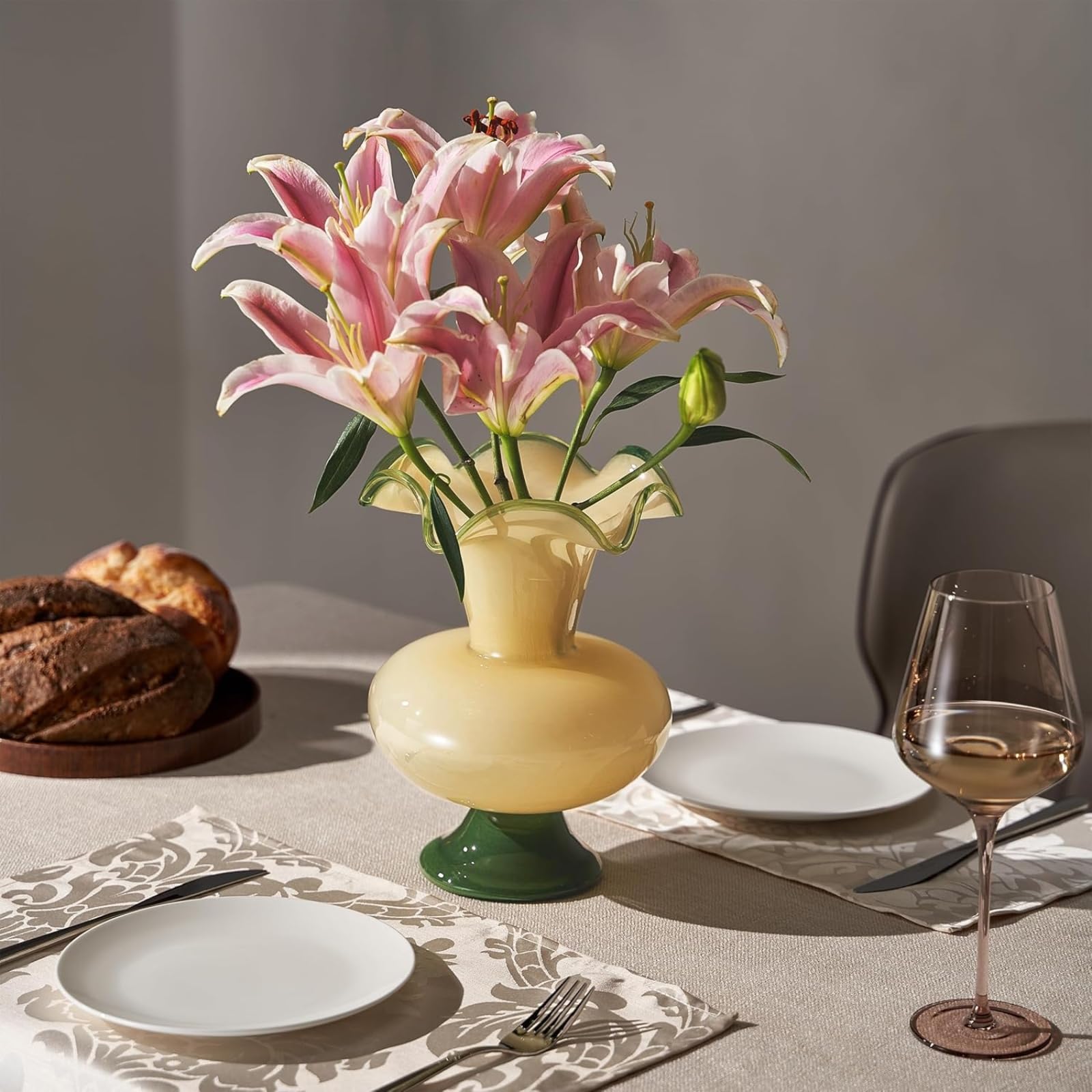 Glass Meadow Hand-Blown Glass Flower Vase holding pink lilies on a dining table with plates and wine.