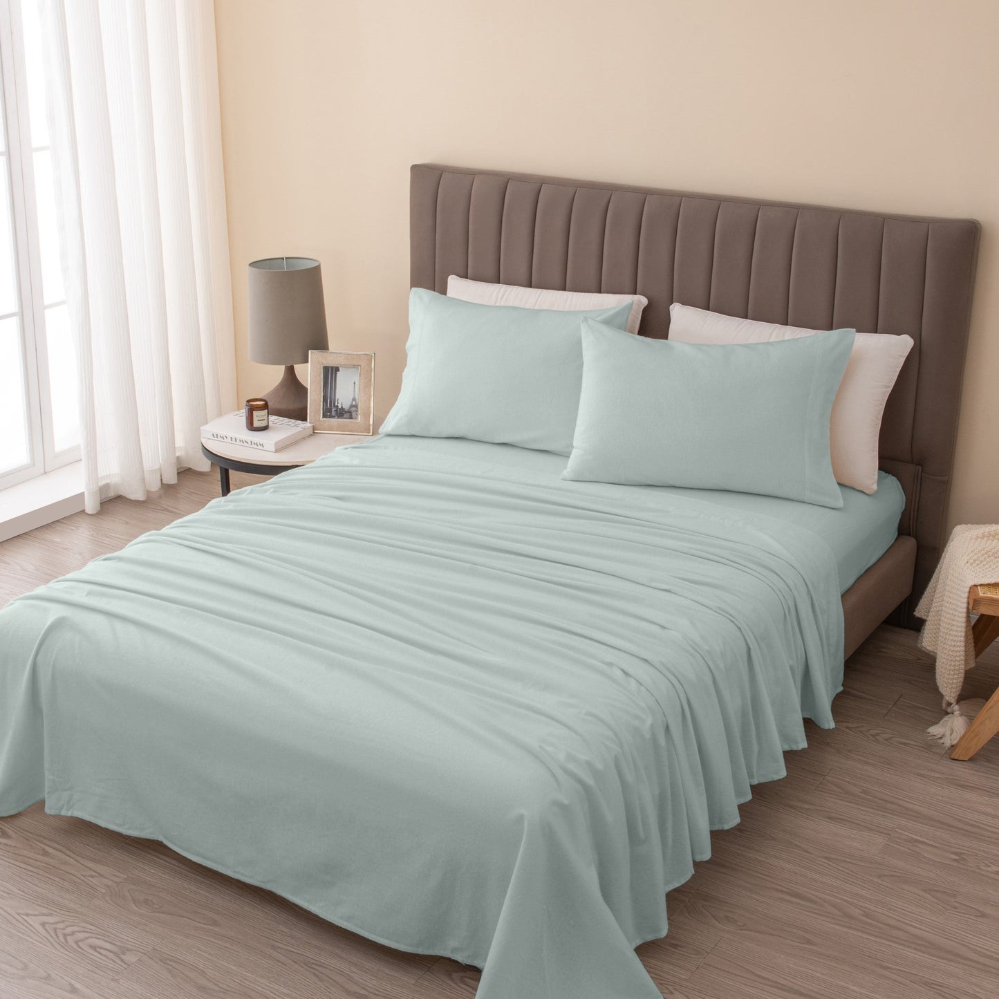 Bed with light blue bedding and brown headboard in a bedroom setting.