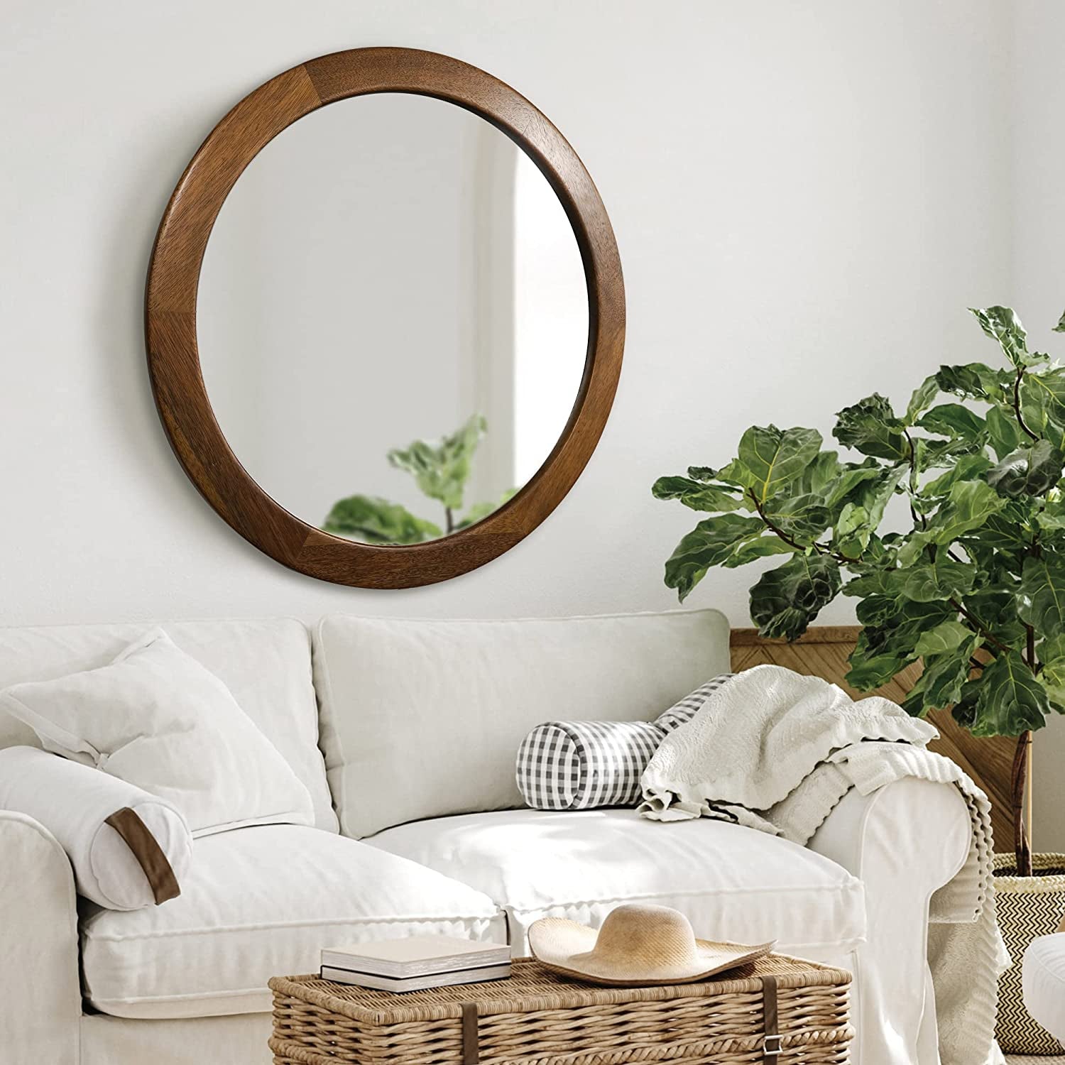 Living room with a white sofa, round wooden mirror, and a plant.