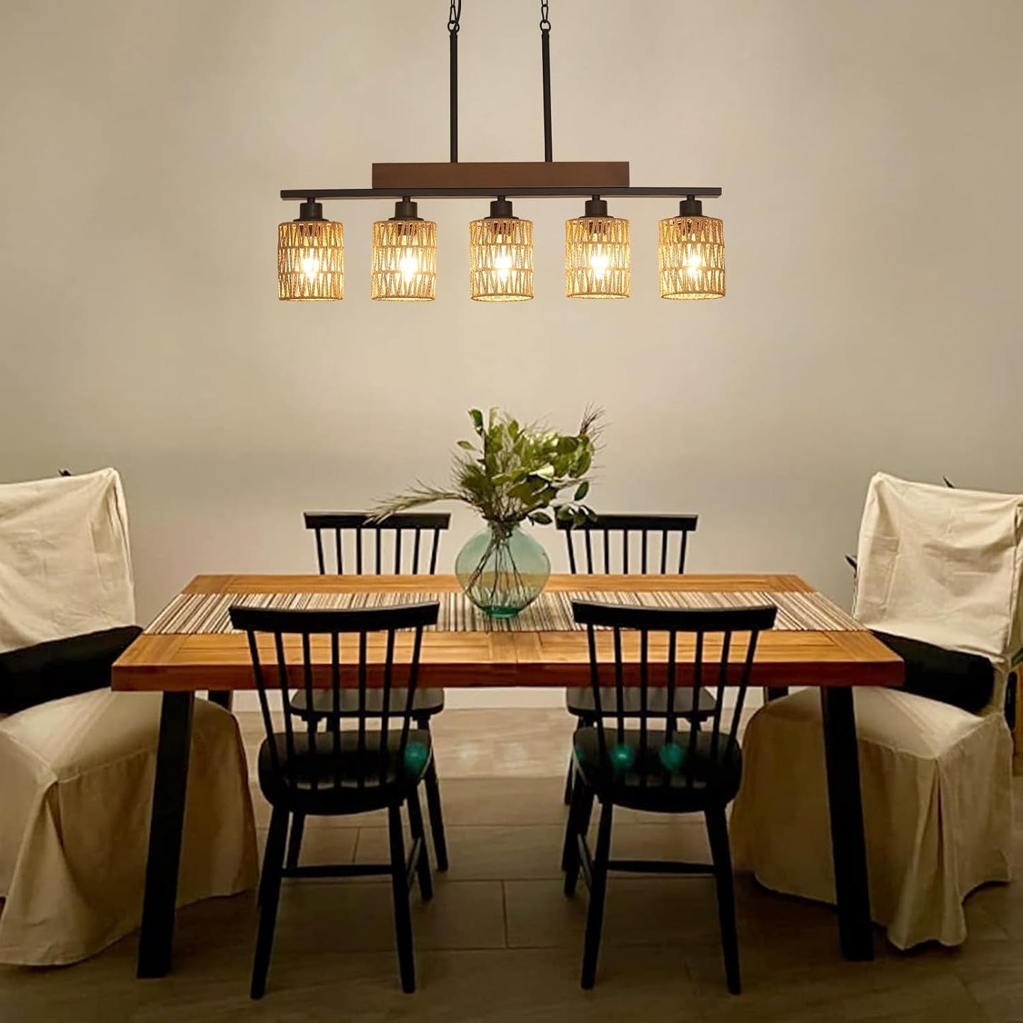 Rattan Farmhouse 5 Light Linear Chandelier Black Lighting illuminating a dining room table with black chairs.