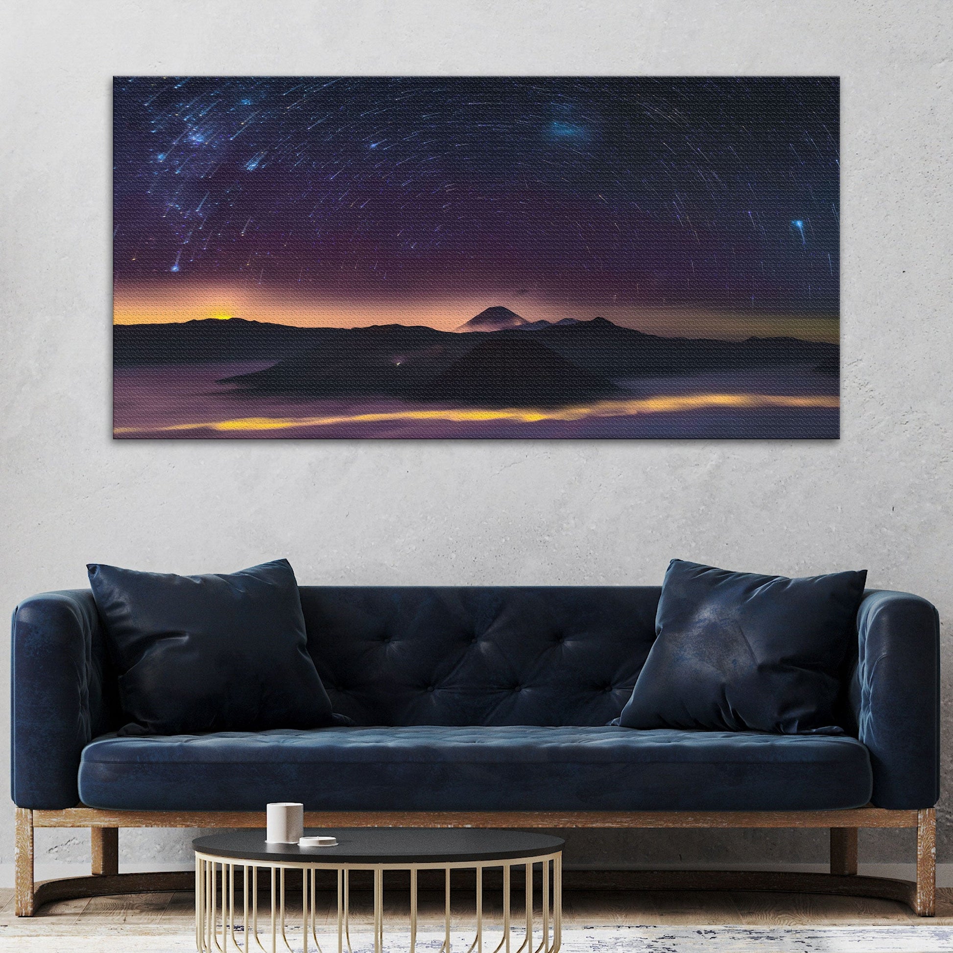Navy blue sofa with decorative pillows in a room with a large wall art of a mountain landscape.