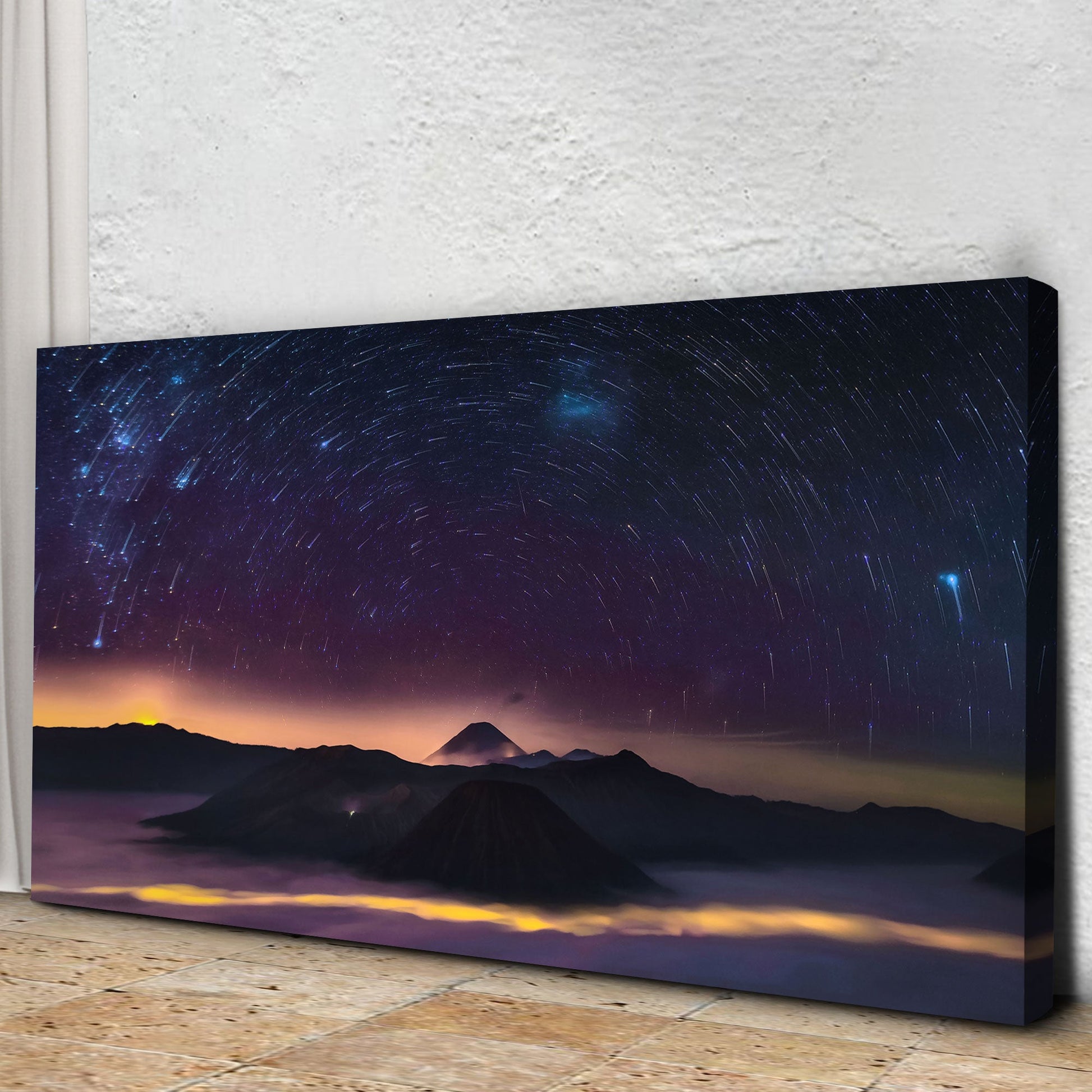 Canvas print of a starry night sky over mountains on a textured wall.