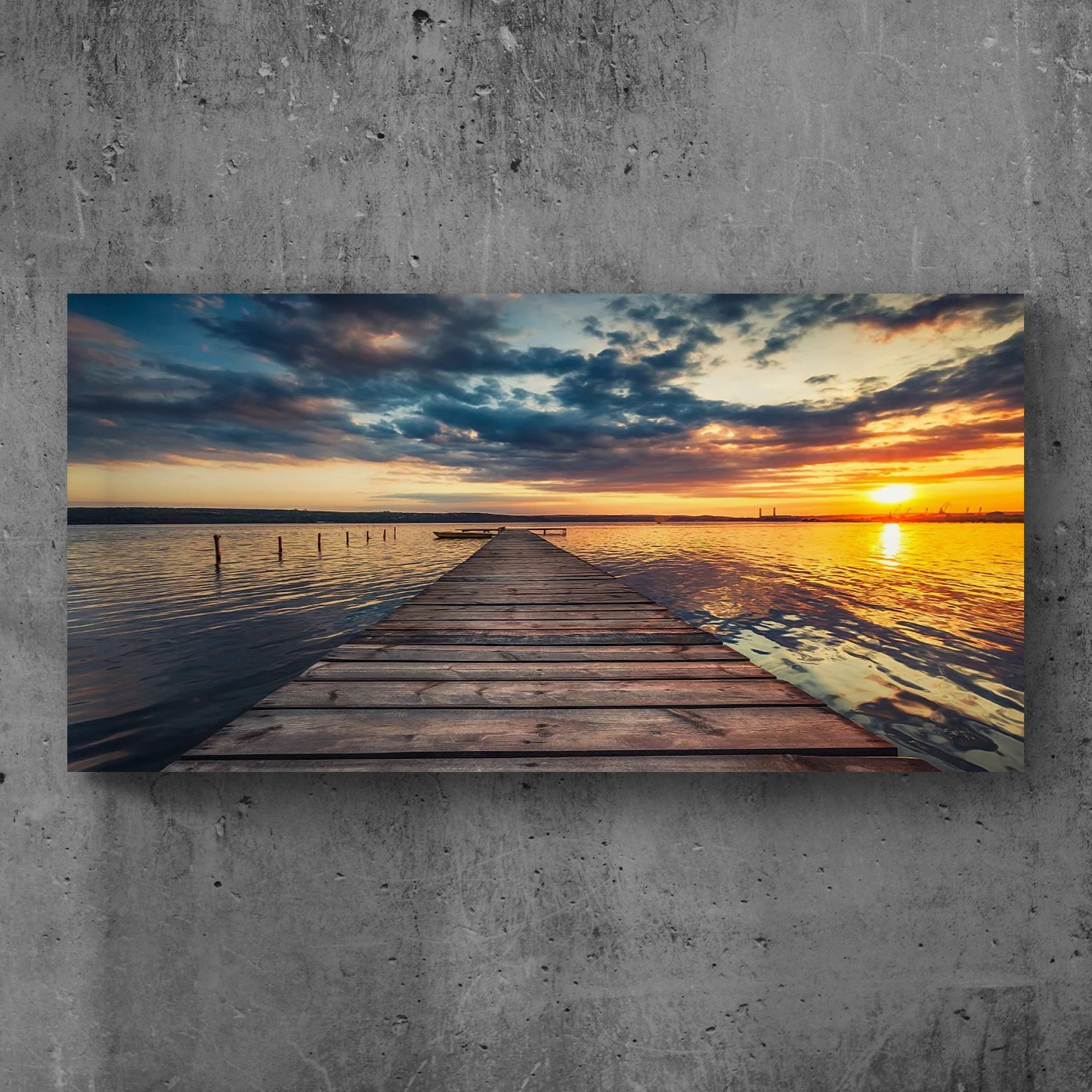 Wooden dock extending into a lake with a sunset sky, on a concrete wall.