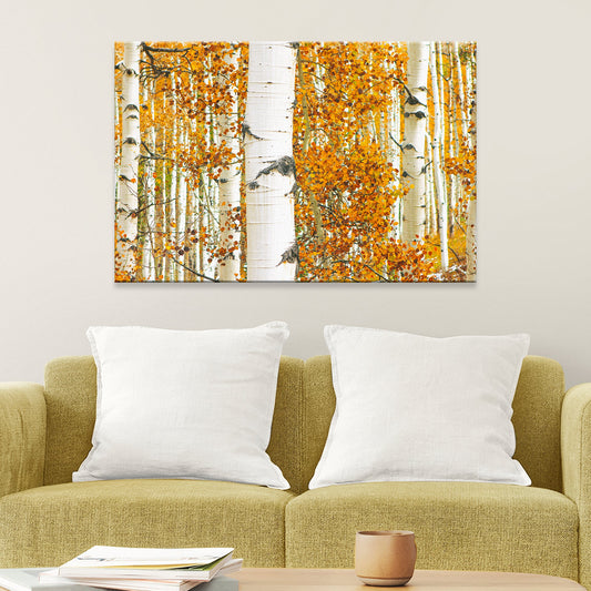 Two abstract paintings of autumn trees with orange leaves on a wall above a green sofa.