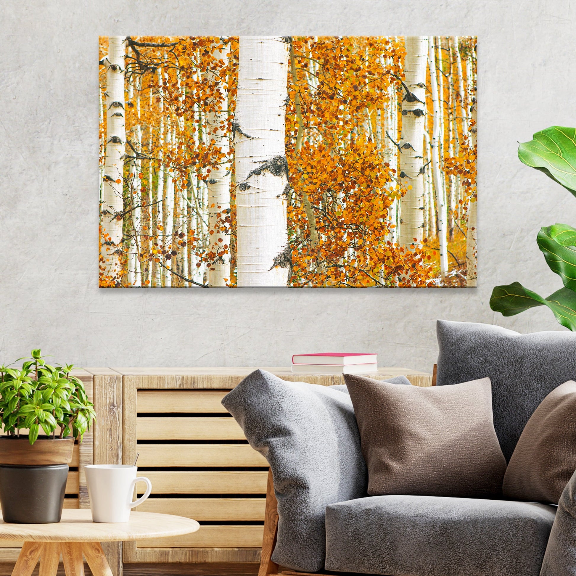 Living room with a sofa, coffee table, and wall art of autumn trees.