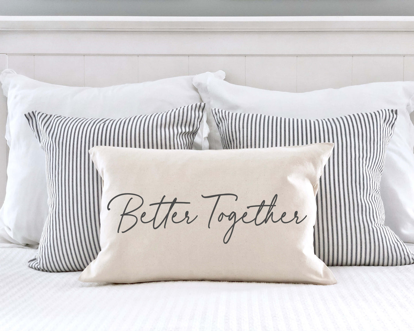 Better Together Valentine's Day Pillow Cover 12x20 Inch on a bed with striped pillows.