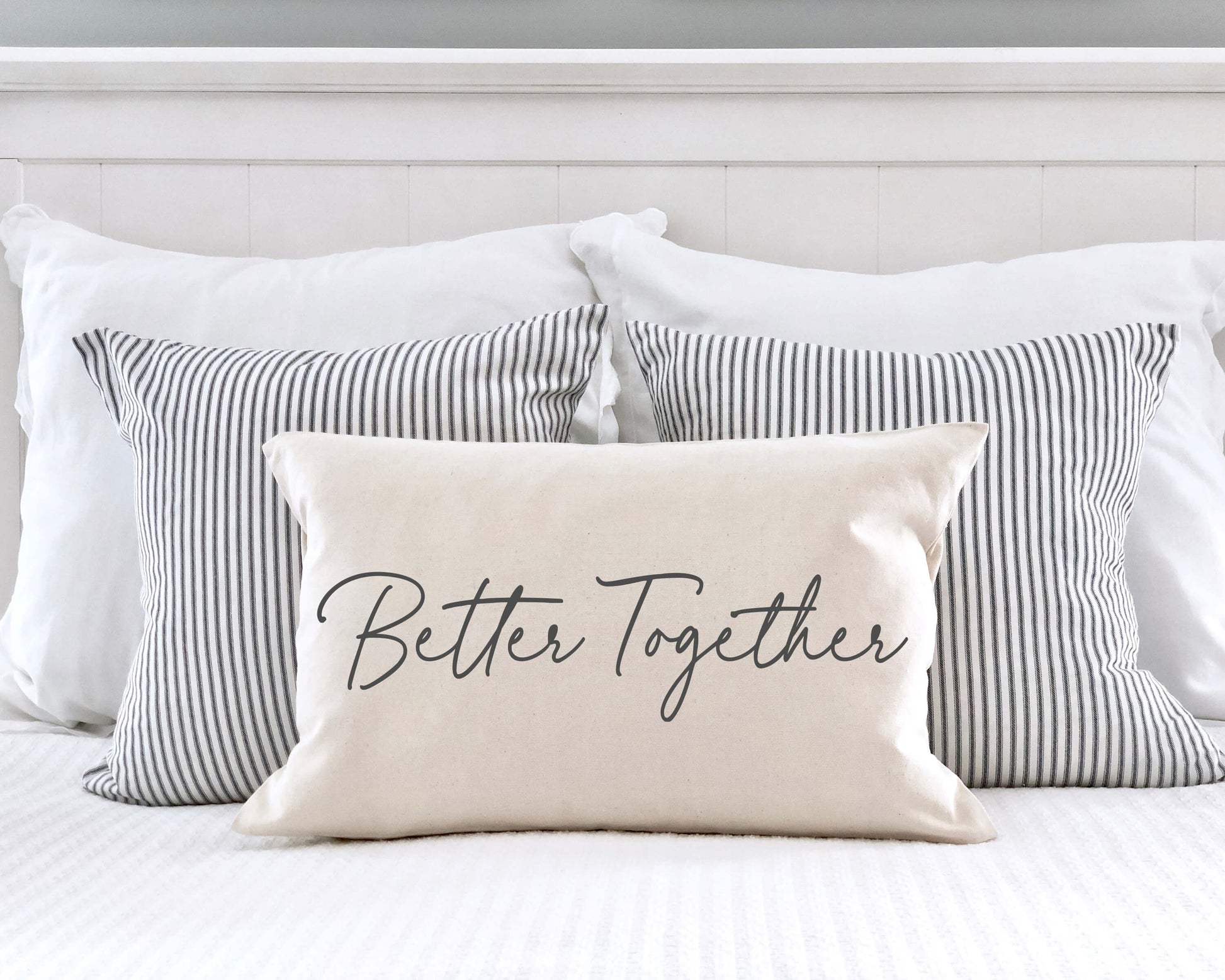 Better Together Valentine's Day Pillow Cover 12x20 Inch on a bed with striped pillows.