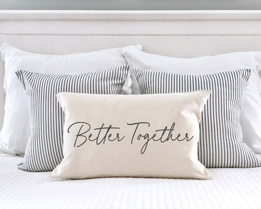Better Together Valentine's Day Pillow Cover 12x20 Inch on a bed with striped pillows.