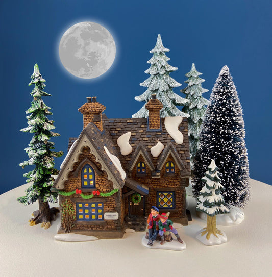 Christmas-themed miniature house with trees and figures against a blue background