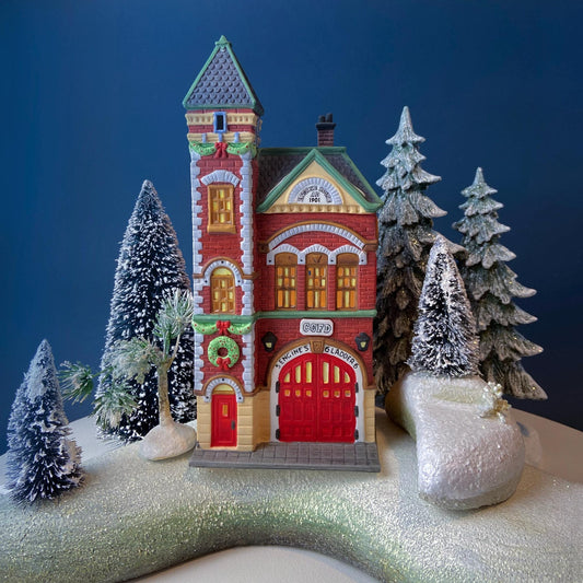 Decorative model of a fire station with trees and snow on a dark blue background