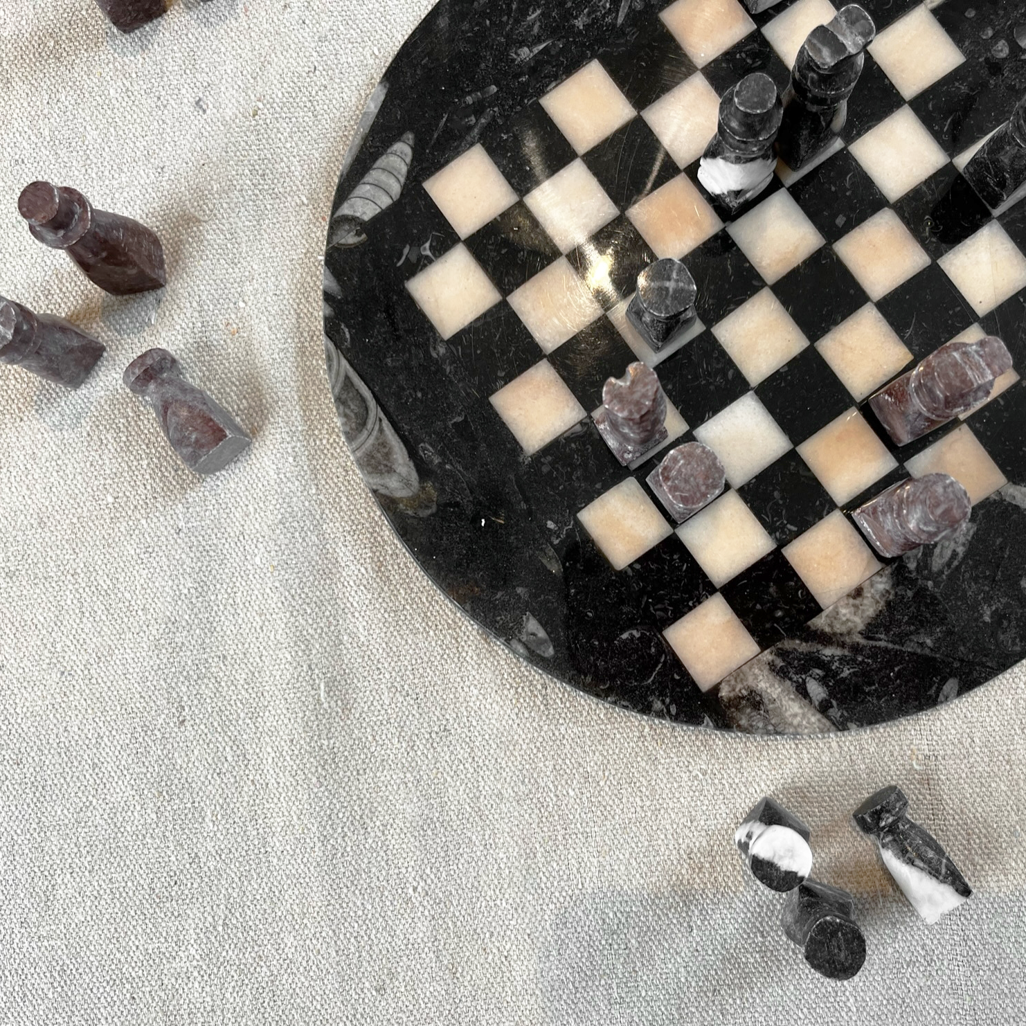 Stone Chess Set featuring a handcrafted stone board and unique pieces on a textured fabric background.