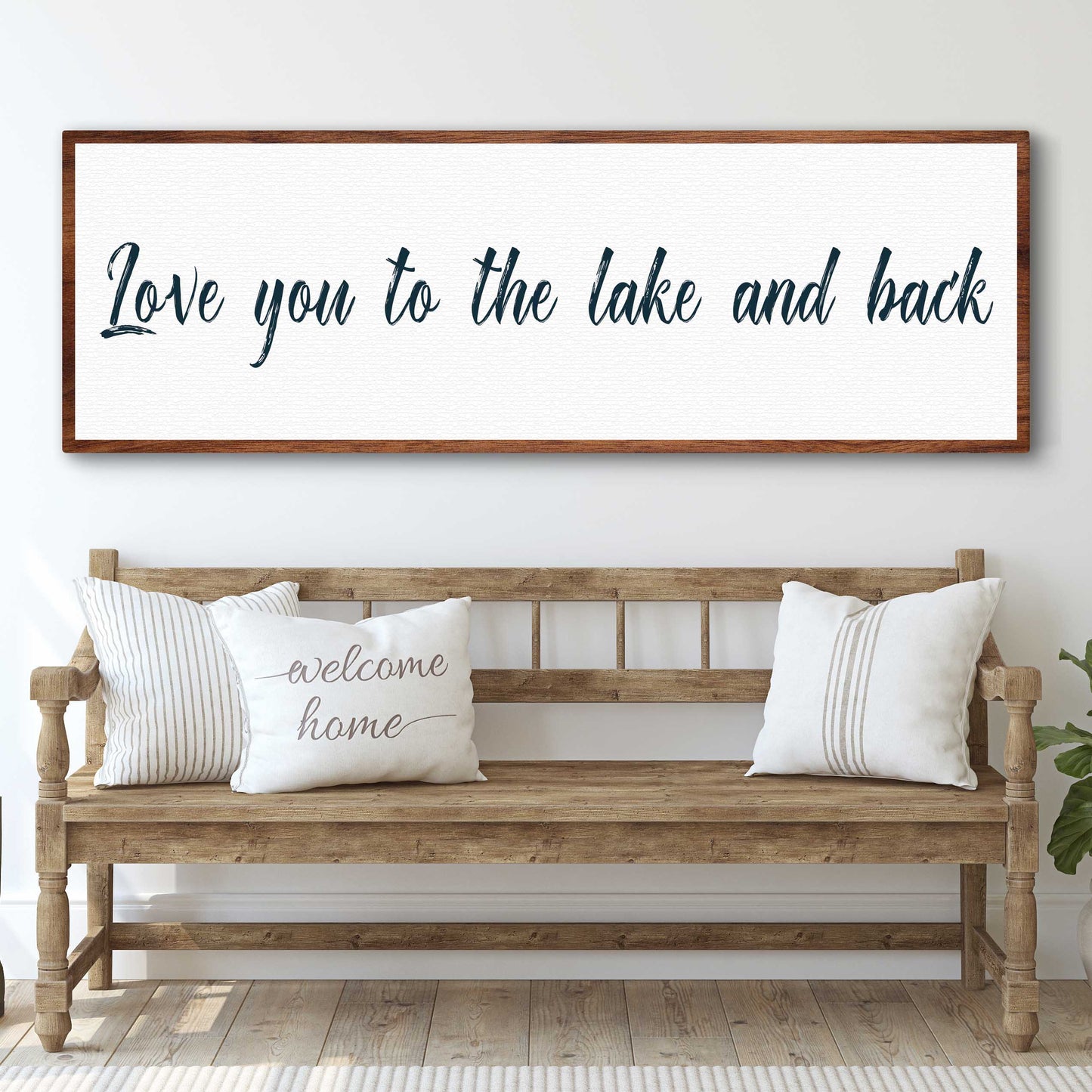 Wooden bench with pillows and a framed sign above it in a room.