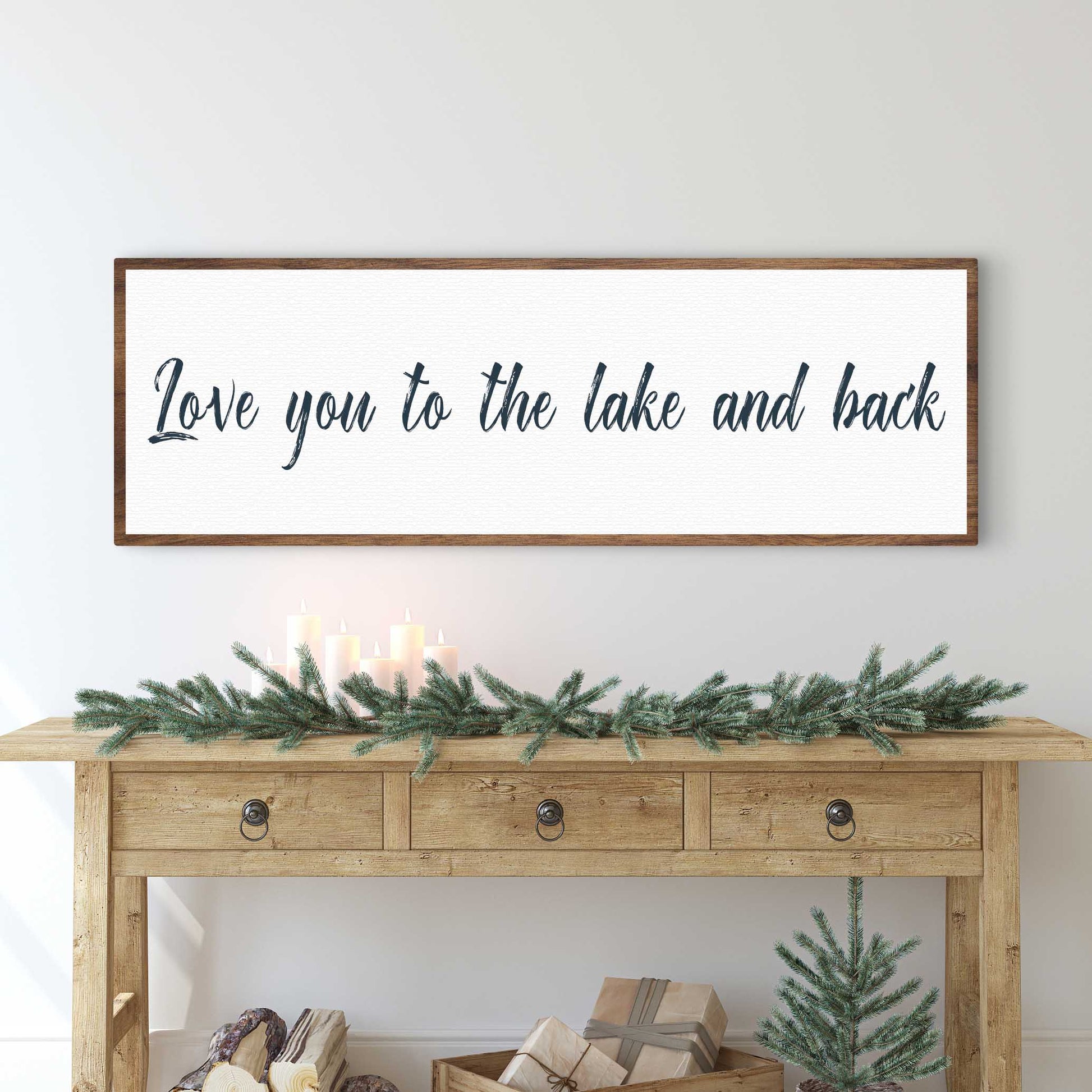 Wooden console table with decorative greenery and 'Love you to the lake and back' sign above.
