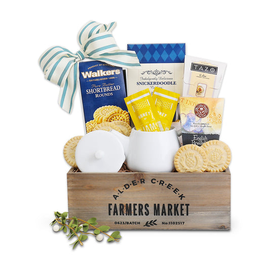 Gift basket with snacks, cookies, and a mug in a wooden crate labeled 'Alder Creek Farmers Market'.