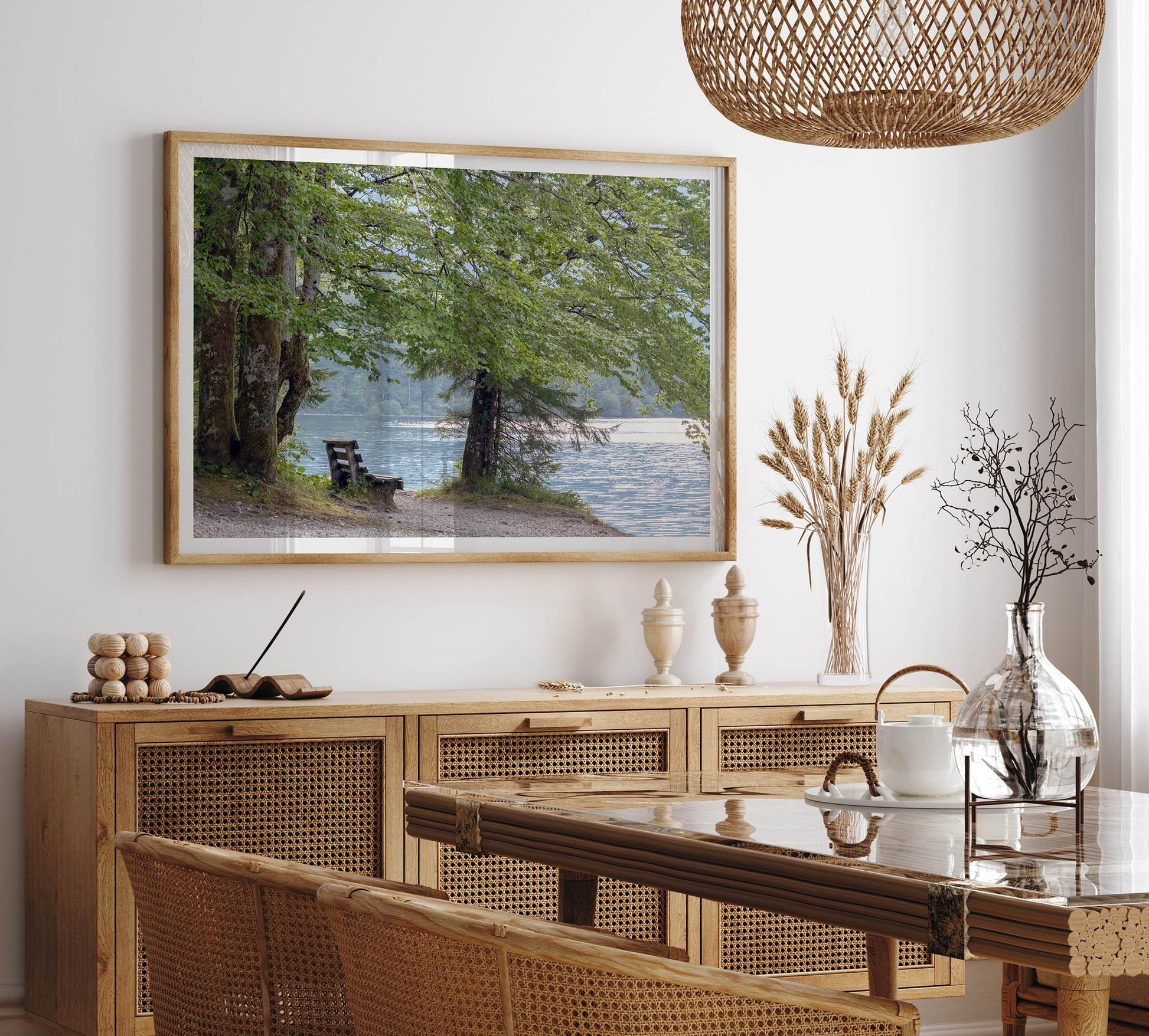 Framed serene lake print of a tranquil lake with a bench under leafy trees, enhancing a modern dining room.